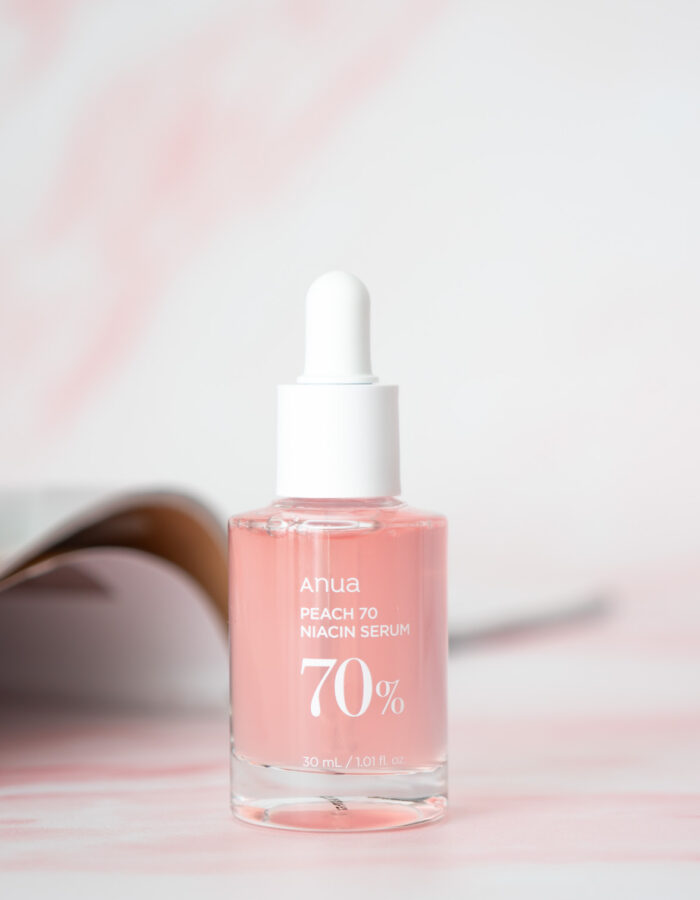 A 30mL Bottle of Anua Peach 70 Niacin Serum on a pink marble background