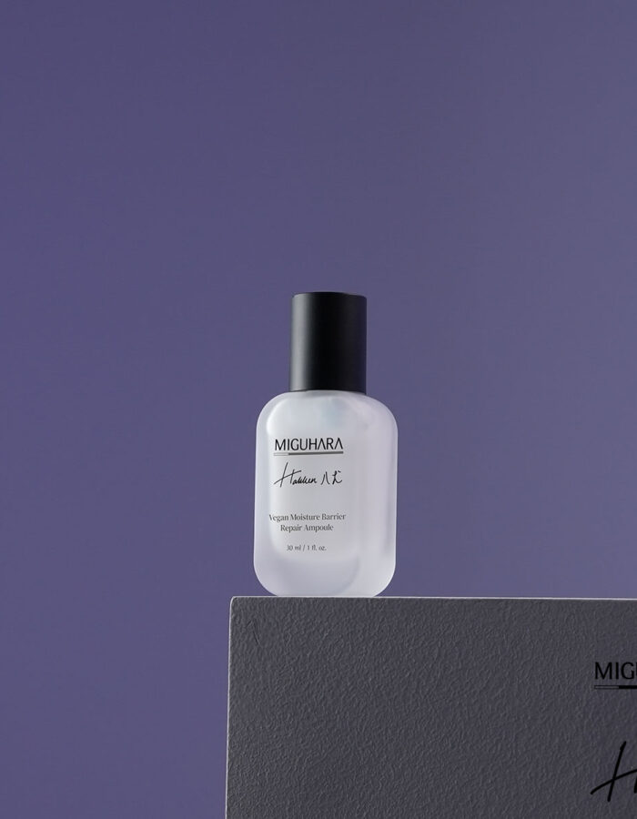 A compact, frosted glass bottle of Miguhara Vegan Moisture Barrier Ampoule, 30mL, featuring a minimalist design with a dropper cap. The ampoule is formulated to strengthen the skin's moisture barrier, providing deep hydration and nourishment for a healthy, radiant complexion.