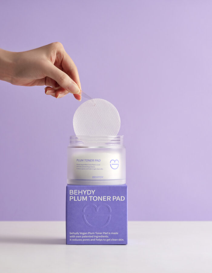 Behydy Plum Toner Pads, 150mL, housed in a clear, elegant container with a secure lid. The packaging highlights the plum-based formula, designed to gently exfoliate and hydrate the skin. Ideal for convenient, mess-free skincare routines.