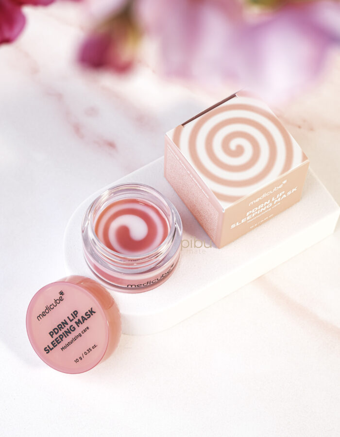Medicube PRDN Lip Sleeping Mask jar with open lid. Showing pink and white swirl balm next to packaging box.