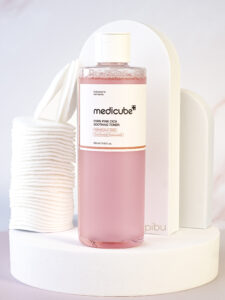 Medicube pdrn pink cica soothing toner Standing on white round platform with cotton round pads on the side