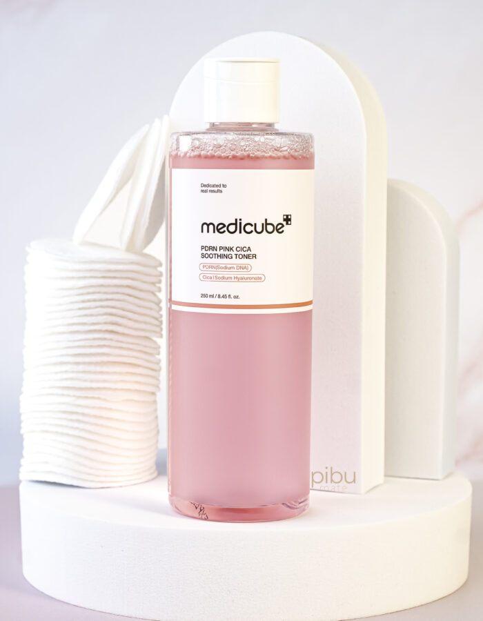 Medicube pdrn pink cica soothing toner Standing on white round platform with cotton round pads on the side