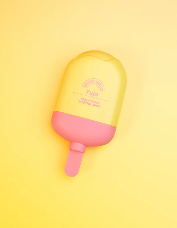 Yellow and pink container of Patch Holic Yuja Brightening Sleeping Mask on a yellow background.