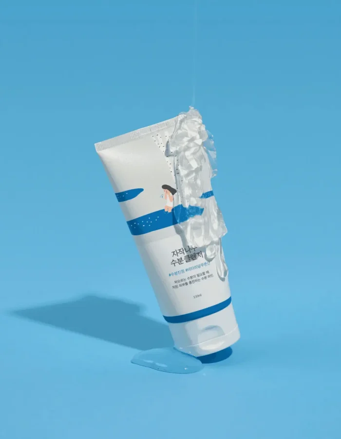 A tube of birch moisturizing cleanser with gel dripping, set against a blue background.