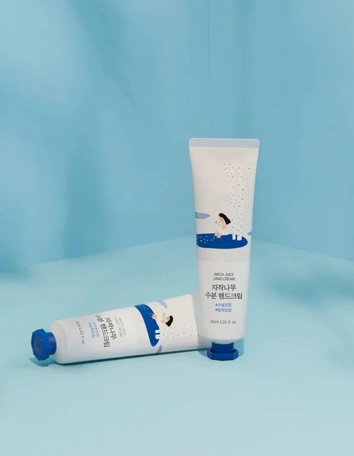 Two tubes of birch hand cream on a light blue background, featuring playful illustrations and product details.