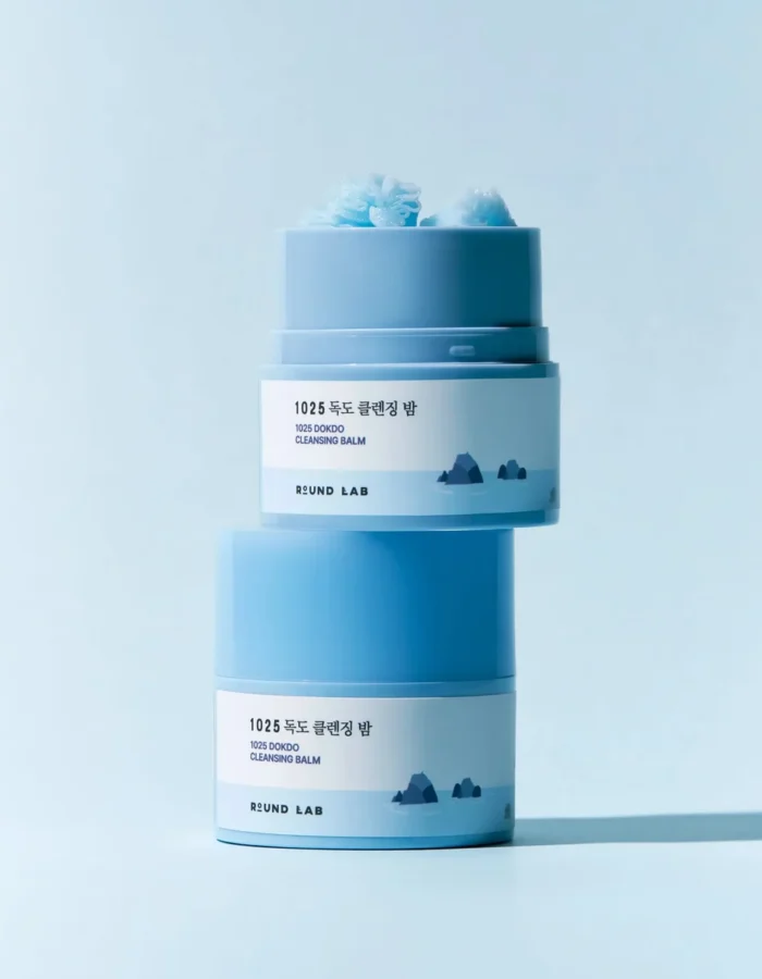 Two jars of 1025 Dokdo Cleansing Balm stacked, featuring a light blue design and mountain graphics on the labels.
