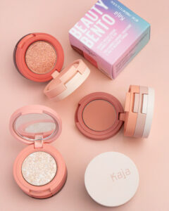 Three stacked eyeshadow compacts in soft pink tones, with a box labeled Beauty Bento in the background.
