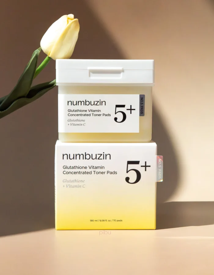 Container of Numbuzin Glutathione Vitamin Concentrated Toner Pads with a white lid and a yellow gradient base, beside a yellow tulip