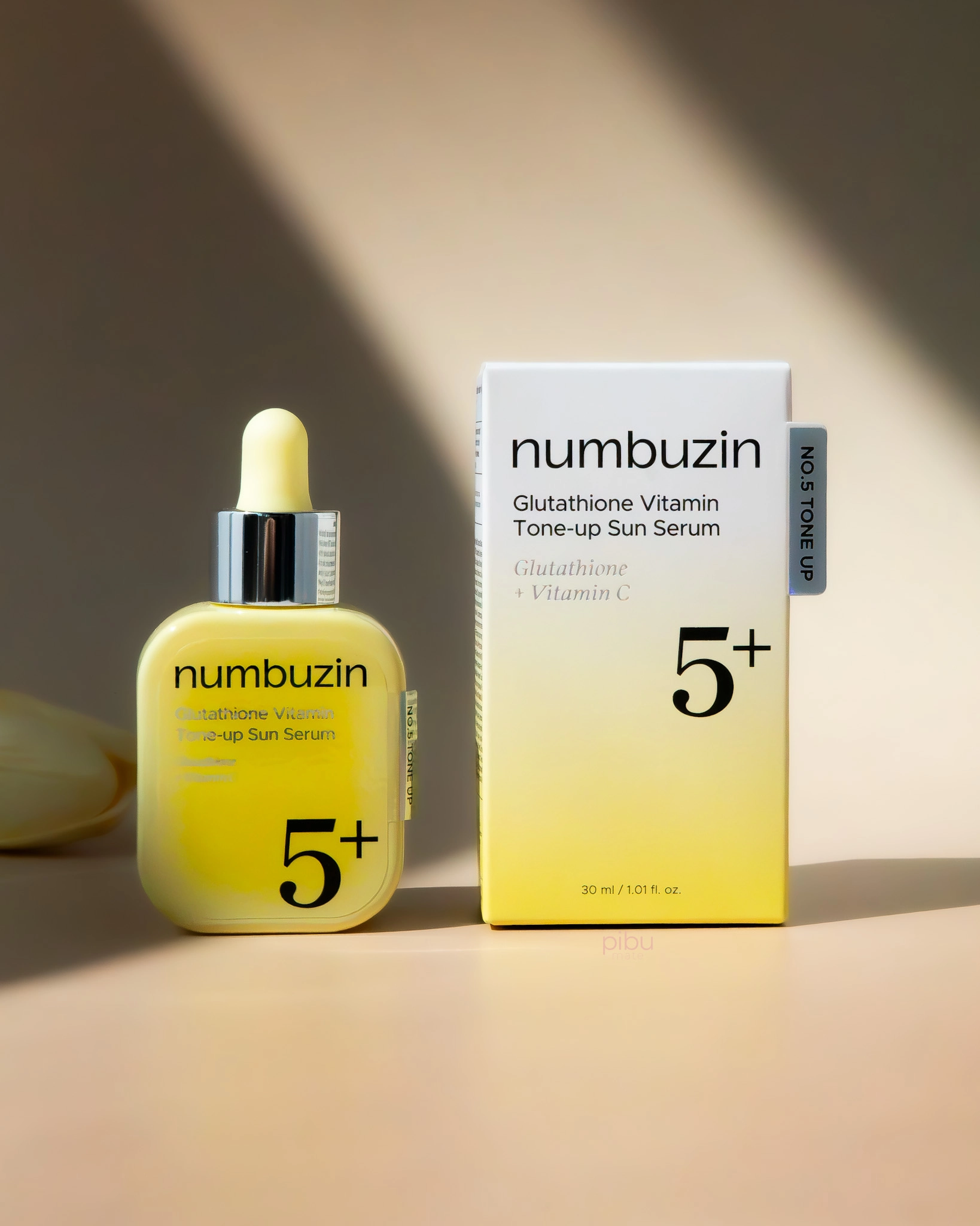 A yellow serum bottle and its box, labeled Numbuzin Glutathione Vitamin Tone-up Sun Serum, on a soft background.